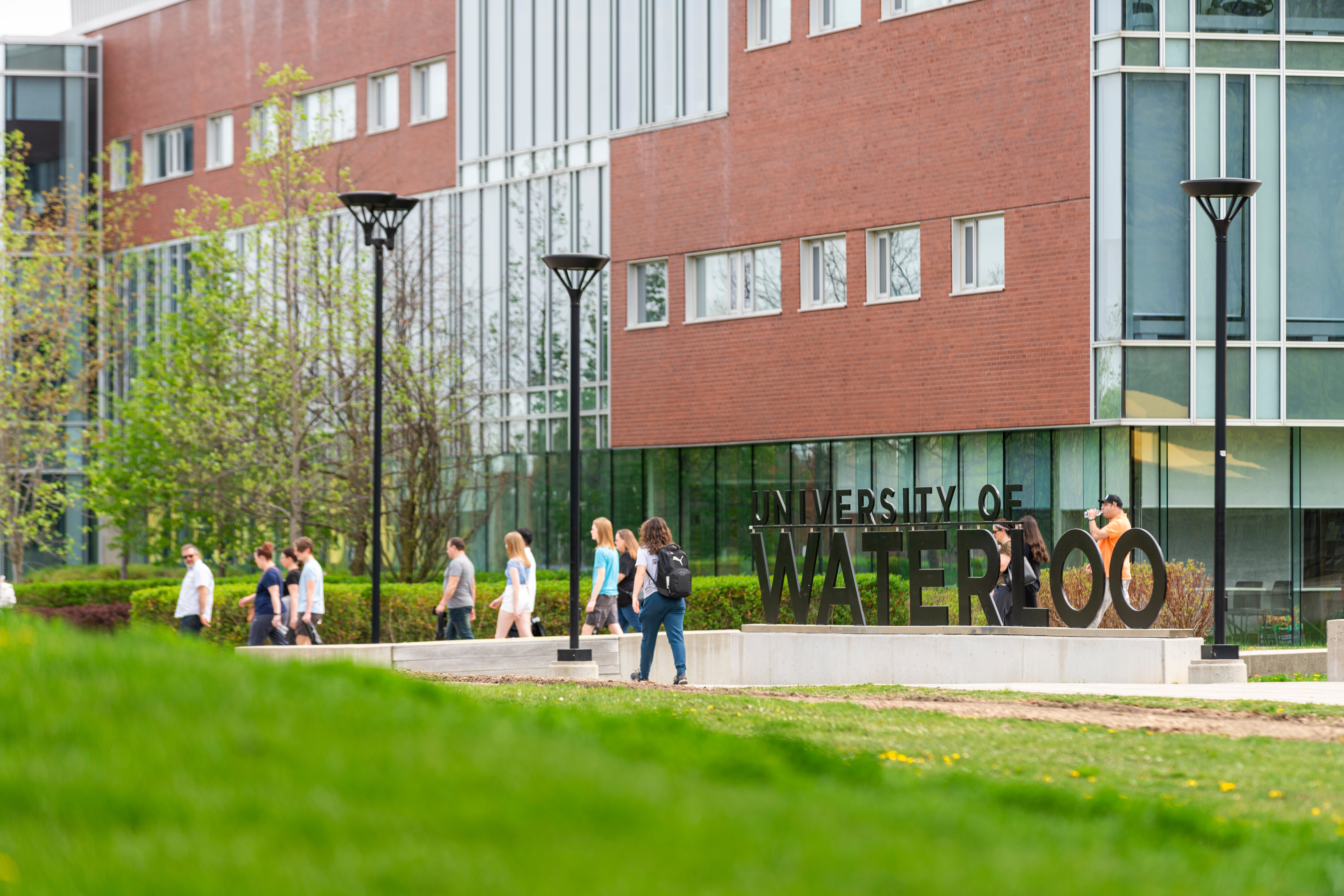 Group of people walking by UW sign in front of TC in summer