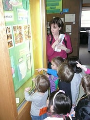 children with teacher looking at art