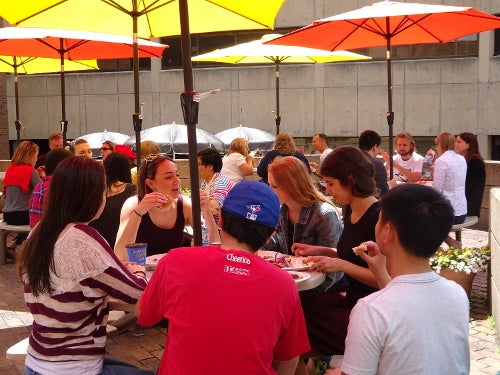Patio with orange,yellow umbrellas with groups of people eating lunch