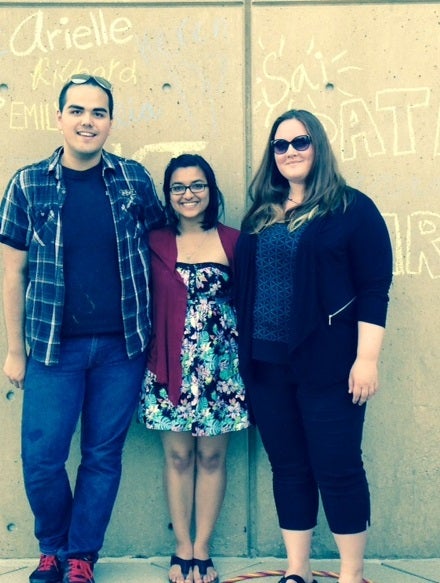 Alex, Sai and Emily in front of chalk signature wall on patio