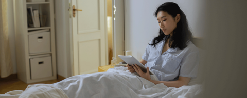 Women in bed holding iPad