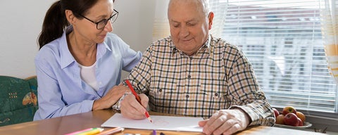 Caregiver with older adult colouring a picture.
