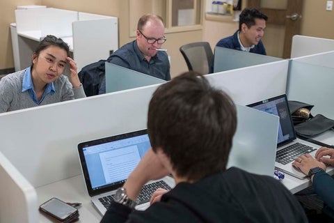 Graduate students working on laptops.