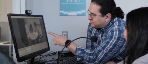 Professor and student looking at computer monitor in health informatics lab.