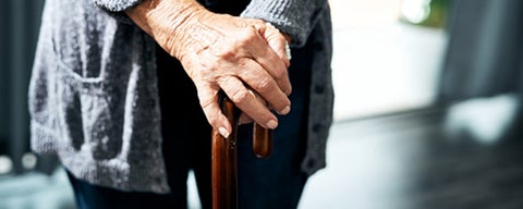 Older adult hands leaning on cane
