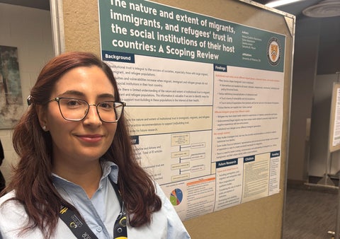Helena Godinho Nascimento in front of research poster at conference.