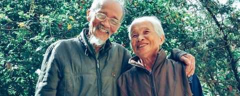 Older couple embracing with greenery in background