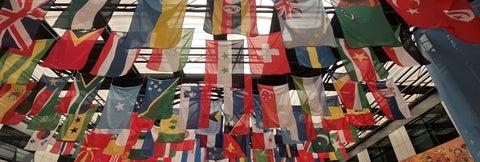 Flags from many countries hanging from the ceiling in a large conference room.