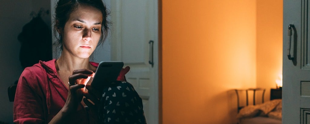 Young person in pajamas looking at cell phone.