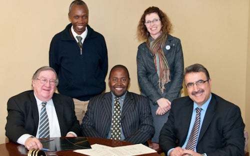 photo of Uganda Christian University and University of Waterloo representatives at table signing agreement