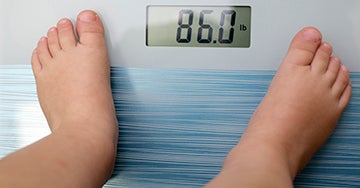 baby's feet standing on scales showing 86 pounds on display