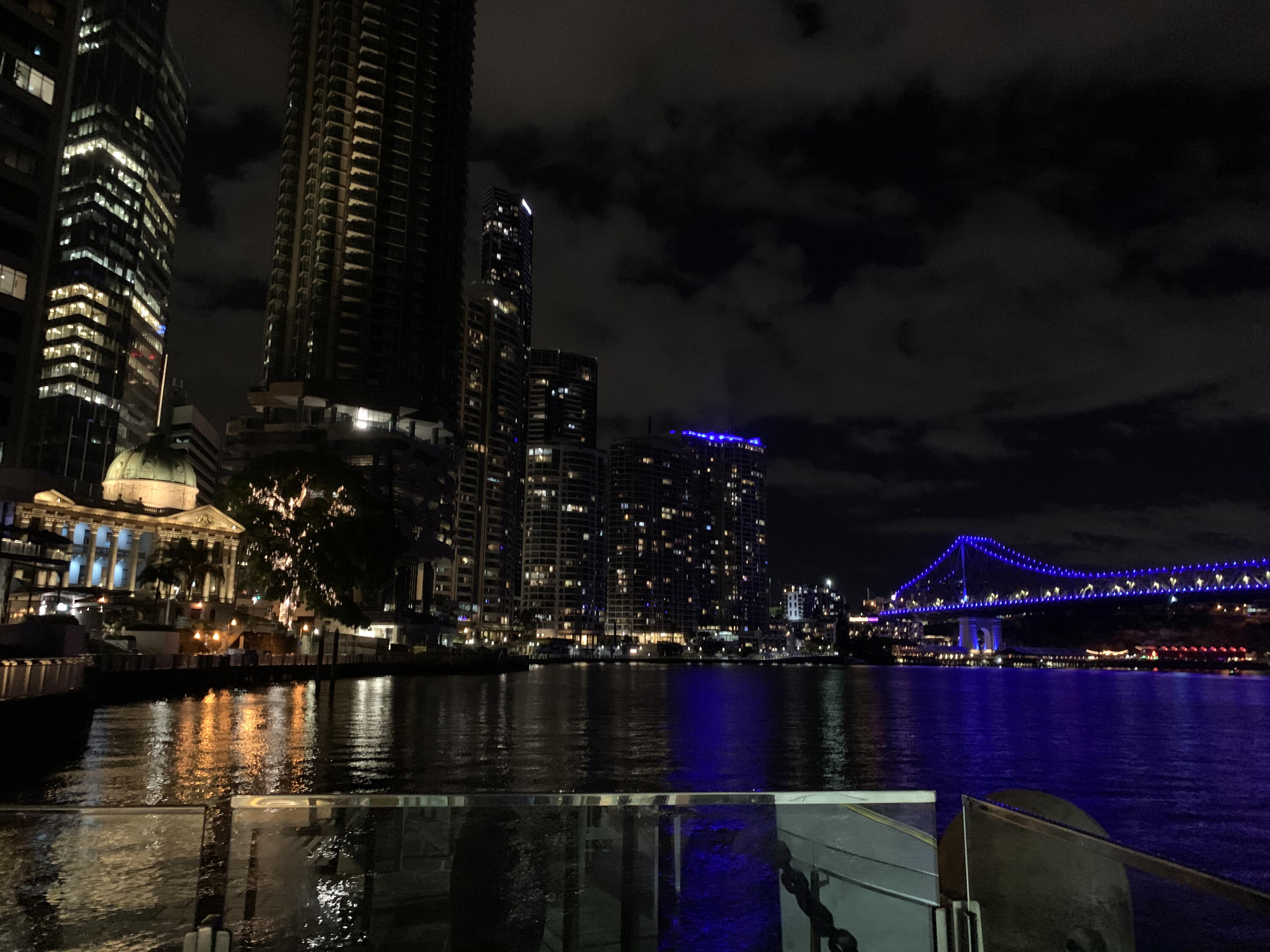 Nightime view of lit city highrises taken from on the water.