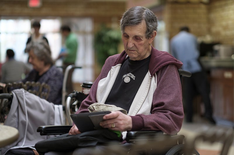 Resident at retirement community reads on a tablet.