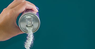 hand holding pop can that is pouring sugar