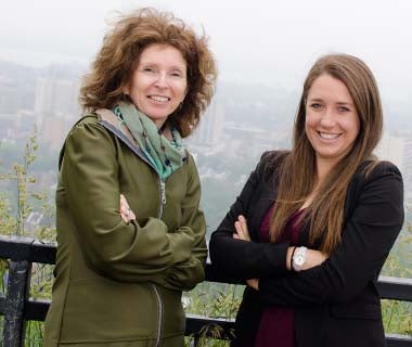 Susan Elliott and Francesca Cardwell in front of foggy city landscape.