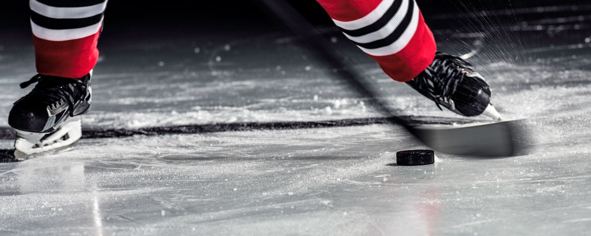 Detail of hockey player on ice with stick and puck