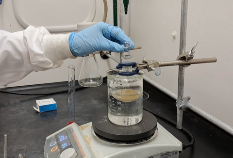 Chemist adding a liquid to a flask inside the fumehood.