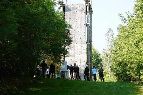 students gathered around the bottom of the rock climbing wall 