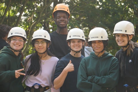 5 students smiling with rock climbing helmets on 
