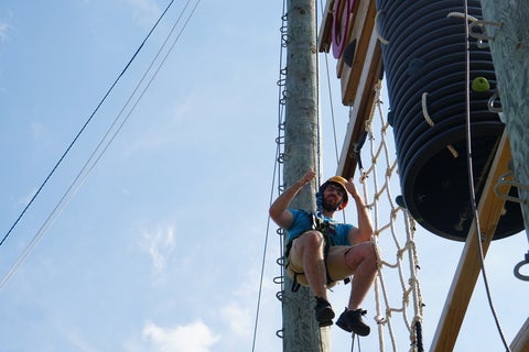 student descending in his harness from high ropes 