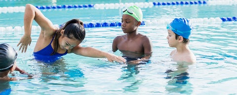 Instructor demonstrating swimming to children.