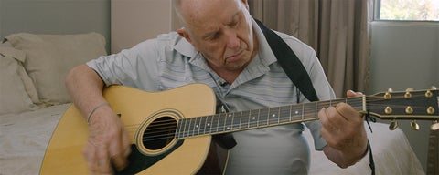 Older gentleman plays guitar.