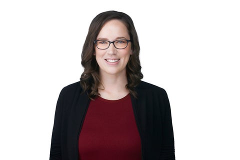 smiling woman with glasses in a suit jacket