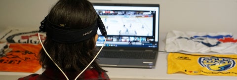 Person wearing headset viewing hockey game on laptop.