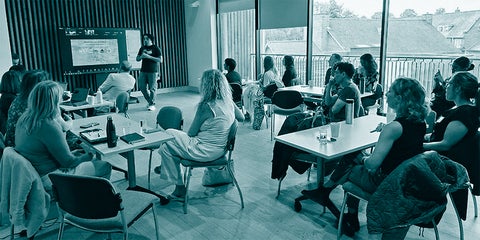 Conference participants in small groups listen to a facilitator.