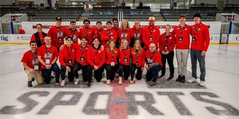 Kennedy and USports coordinators and volunteers on hockey rink.