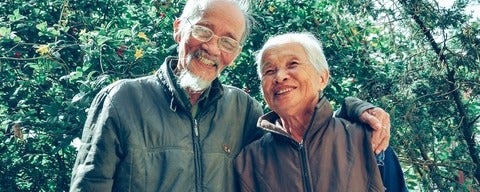 Older couple smiling outside.