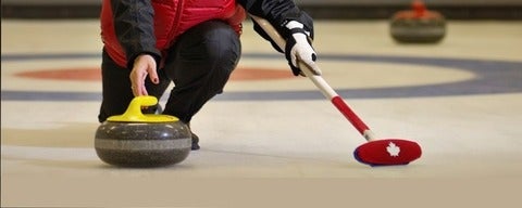Curler releases curling stone down ice.