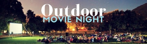 Photo of an outdoor movie screen with people watching in a field. 