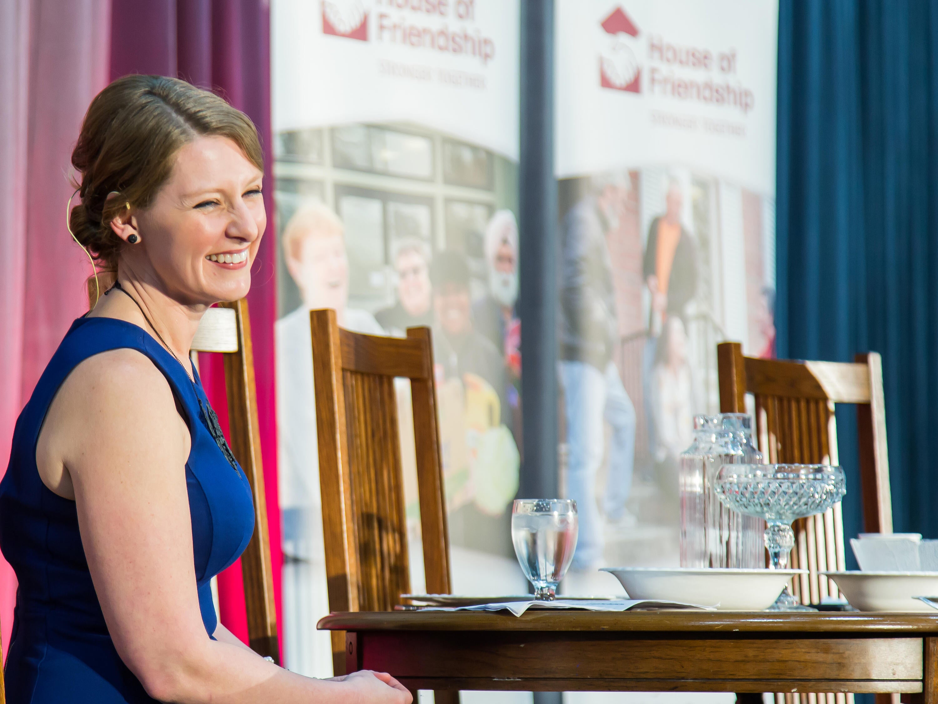 Jessica Bondy smiling while sitting next to a table at an event