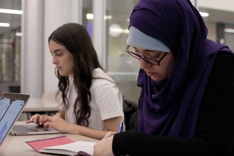 Two graduate students work at a table in the Hagey Hub study room