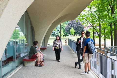 A group of undergrad students talking beneath the arches of the Dana Porter Library