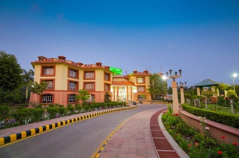 A landscaped university campus with a road leading to a large building.