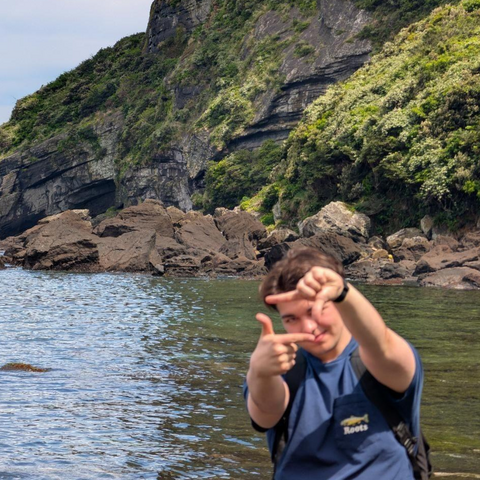Student posing in front of water and mountain 