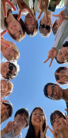 Students in a circle looking down at the camera
