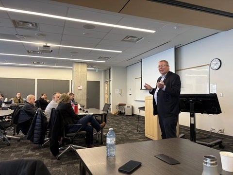 One person standing at the front of a classroom talking to attendees. 