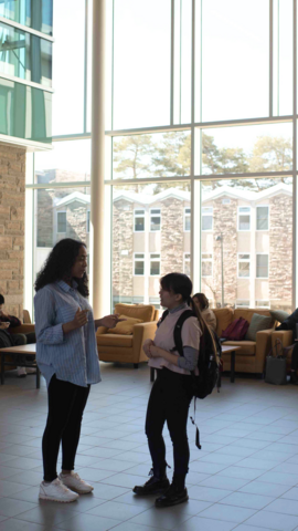 Two people standing facing each other in the Renison atrium.
