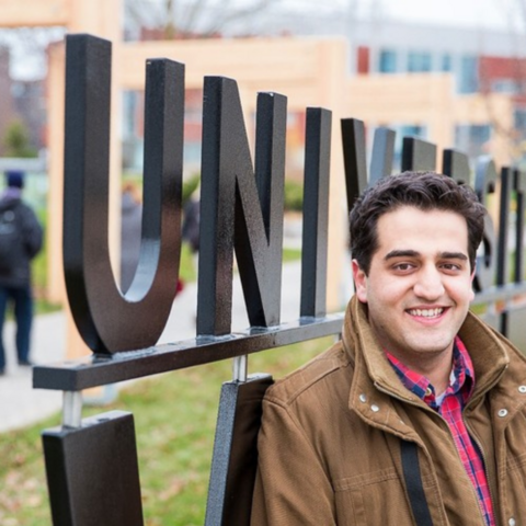 Student standing beside the University of Waterloo sign. 