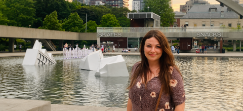 Chelsey Freeman smiling in front of a lake with a bridge and tall buildings in the background