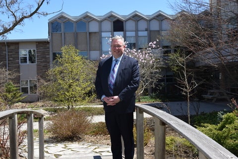 Dr. Marc Jerry standing on the bridge in the Renison courtyard. 