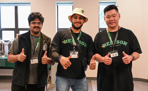 Three male students holding thumbs up wearing Renison t-shirts