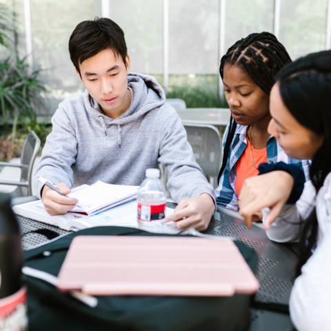 Three students sitting at a table studying. 