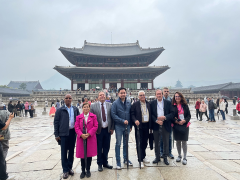 Wendy standing with some other attendees at the Gyungbokgung Palace in Korea. There are 7 people in total standing in a large public square. 