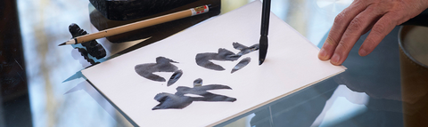 Someone writing Japenese charaters on a paper