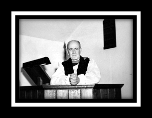 Bishop Renison standing at a pulpit wearing robes. 