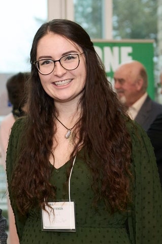 Rachael Fowler at a recent event. She is wearing a green dress and glasses, and is smiling at the camera.
